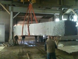 A slab of memorial granite lifted by crane inside the cutting shed