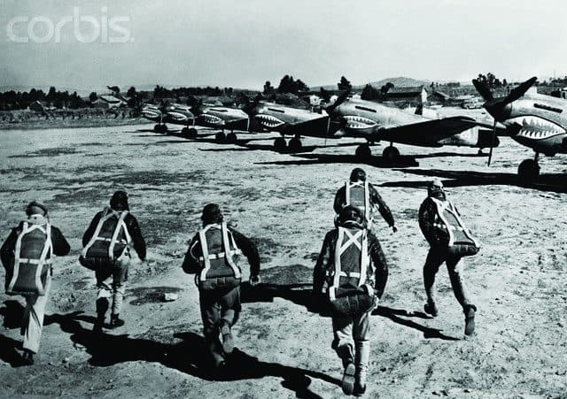 Pilots running for their fighters lined up along a airstrip