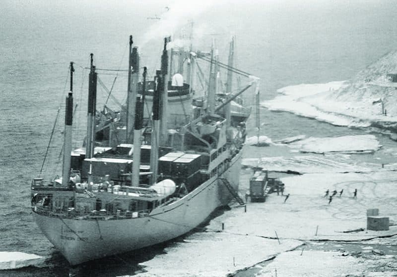 A merchant ship aground and damaged on a shoreline